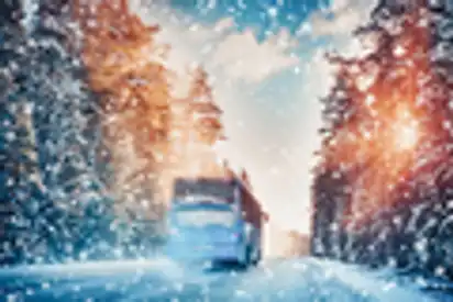 Bus auf Asphaltstraße an einem schönen Wintertag auf dem Land bei Schneefall